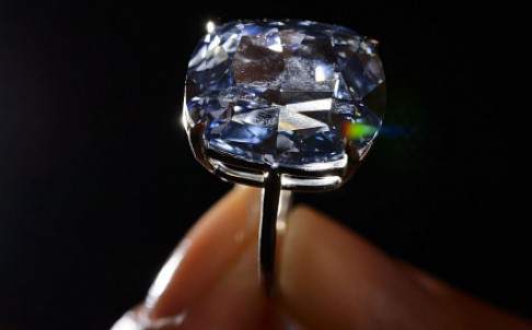 The mystery surrounding the identity of a Hong Kong-based diamond buyer who now owns three of the world’s most expensive gems has been revealed: billionaire fugitive Joseph Lau Luen-hung has confirmed to the South China Morning Post that he was the buyer of the diamonds, and that he had renamed them after his seven-year-old daughter Josephine. The rare and flawless 12.03 carat “Blue Moon Diamond” sold on Wednesday for 48.6 million Swiss francs (US$48.4 million), setting world records for any gemstone at auction, Sotheby's said. Lau, the former chairman of Chinese Estates Holdings, is listed by Forbes as the sixth richest man in Hong Kong and 114th wealthiest globally, with estimated assets worth US$9.8 billion as of November. He is also a fugitive, after being jailed in absentia in Macau in March last year for his part in a bribes-for-land racket involving Ao Man-long, the most corrupt public official ever brought to justice in the city's history. He received a five-year jail term, but has not served one day in prison because the former Portuguese enclave does not have an extradition treaty with Hong Kong.  Macau's Court of Second Instance yesterday rejected appeals by Lau and Steven Lo Kit-sing against their bribery and money laundering convictions. The court upheld sentences of five years and three months against the pair. The sale came only one day after Lau paid 28.7 million Swiss francs for a magnificent 16.08 carat pink diamond at Christie’s. The pink stone was promptly renamed the “Sweet Josephine”. The blue has been renamed “The Blue Moon of Josephine”. Josephine's mother is Lau’s girlfriend, called Chan Hoi-wan, a former entertainment reporter. The cushion-shaped blue stone, mounted on a ring, has the top grading of fancy vivid blue. A pre-sale estimate put its value at between US$35 million and US$55 million. “It is a new record price for any gemstone and per carat,” David Bennett, worldwide chairman of Sotheby's international jewellery division, told a packed showroom in Geneva that erupted into applause on Wednesday. Bennett said the buyer had immediately renamed the stone, noting that it had also set a world record for any jewel at more than US$4 million per carat. “For me the Blue Moon was always the blue diamond of my career. I've never seen a more beautiful stone - its shape, colour and purity. It's a magical stone,” Bennett said. Lau and fellow Hong Kong property developer Steven Lo Kit-sing were each given jail sentences of five years and three months by Macau's Court of First Instance last year after being found guilty of corruption and money laundering. But they will not serve any time unless they return to the city voluntarily. The court found that Lau and Lo offered a HK$20 million bribe to disgraced public works chief Ao Man-long to secure the site for their La Scala luxury development. Lau is also known as a collector of artworks and wine. His passion for art was revealed when he snapped up Andy Warhol's famous painting of Mao Zedong for US$17.4 million and Paul Gauguin's 1892 painting Te Poipoi (The Morning) for US$39.2 million - the highest amount paid by a Hongkonger for an artwork. Born in 1951 in Hong Kong with family roots in Guangdong's Chaozhou, Lau graduated from a university in Canada in 1974, and joined his family's business, which made ceiling fans. Lau built his wealth on the Hong Kong stock market in the 1980s, but analysts have pointed out that the tycoon, with his younger brother Thomas Lau Luen-hung, was better known for corporate takeovers than stock investments. Their reputation as corporate raiders was created when their investment unit, Evergo International Holdings, made a hostile bid for the Kadoorie family's Hongkong and Shanghai Hotels in 1987. Evergo, which listed in 1983 as a ceiling fan manufacturer, was subsequently delisted in 1993 to become a subsidiary of Chinese Estates Holdings. Apart from his relationship with Chan, Lau has another a long-time partner, Yvonne Lui, who gave birth to two children with the tycoon.  He also has two other children from his previous marriage to Bo Wing-kam. They divorced in 1992. Lau paid a record HK$1.4 million for a car number plate bearing the characters "1 LOVE U" during a Transport Department auction of personalised plates in 2006. The plate was used on a Mercedes-Benz for his partners, according to local media reports.